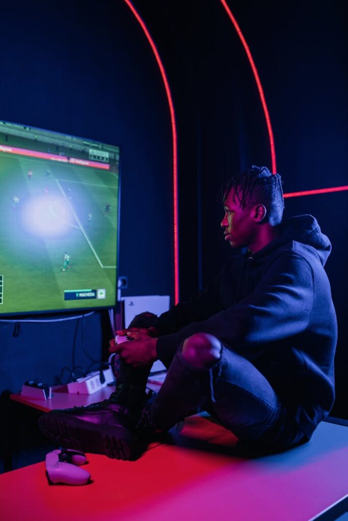 A young adult man in a black hoodie intensely playing video games indoors.