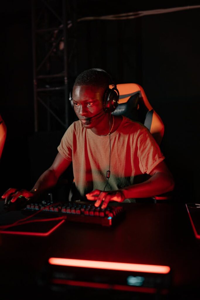 Young adult man gaming intensely at a computer setup with vivid red lights.